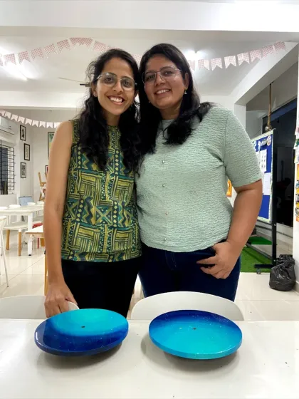 Two friends with their finished resin clocks, showing off the different color combinations they chose.