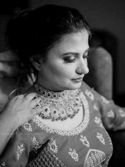 A beautiful black and white photo of the bride getting her necklace adjusted. This artistic shot focuses on the quiet, final touches before the ceremony.