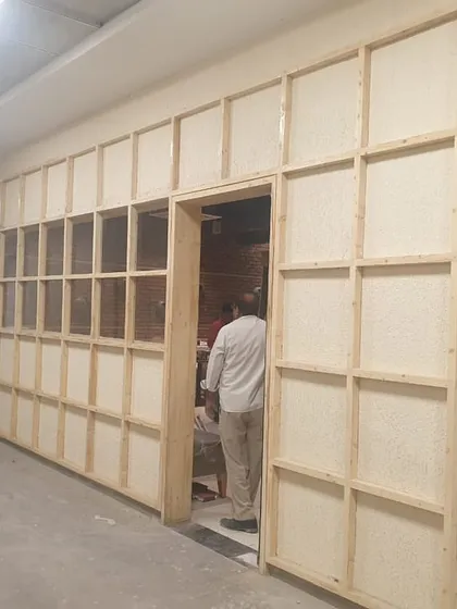 The "before" shot of an entrance wall at Yoko Sizzlers, showing the custom wooden grid frame we built to house the art installations.