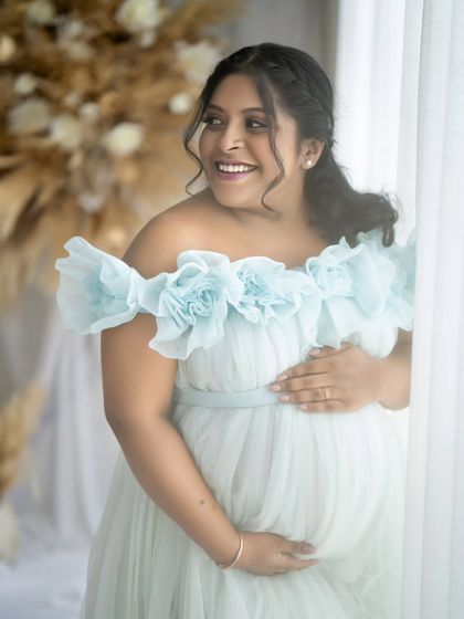 The joy of pregnancy is written all over her face. This candid, happy shot captures her beautiful smile, framed by the soft ruffles of her light blue gown.