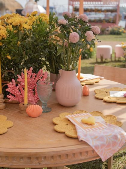 A close-up of the brunch tablescape, featuring flower-shaped placemats, colorful candles, and fresh yellow and pink flowers.