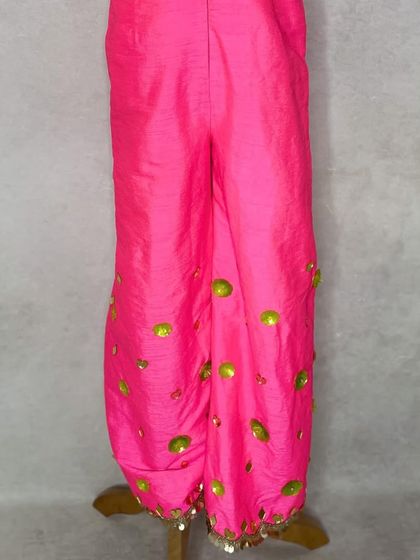 A detail shot of the fluorescent pink jumpsuit, showing the sequin work on the pants.