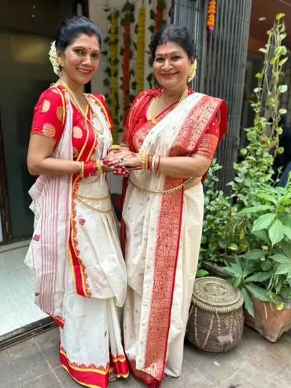 Two generations celebrating Durga Puja together, both in beautifully draped Bengali sarees.
