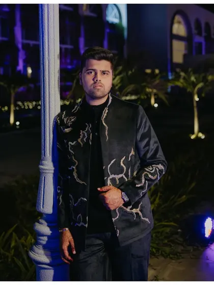 A stylish solo portrait of the groom at the Sangeet. The cool-toned lighting and his confident stance create a modern and sophisticated image.