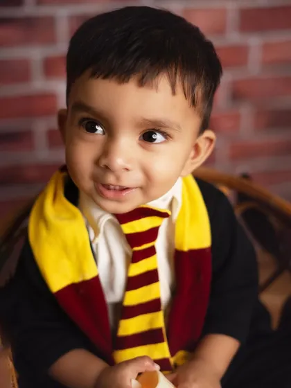 A close up of our little wizard, looking curious and magical. The Gryffindor scarf and tie are perfect details for any Harry Potter fan.