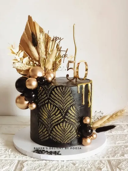 A bold and mysterious black and gold cake for a 50th birthday. The intricate stencil work and dramatic color combination make this a truly captivating and luxurious centerpiece.