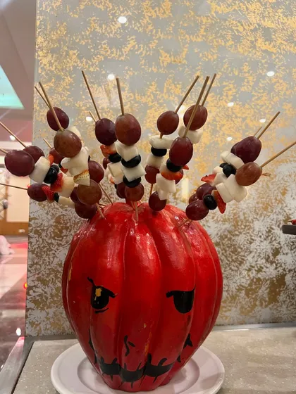 A creative fruit display for a Halloween party. We turned a pumpkin into a vase for fruit skewers, a healthy and festive addition to the dessert table.