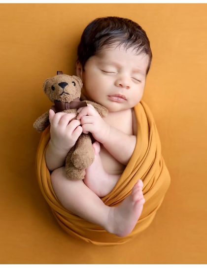 A classic swaddled pose with a beloved teddy bear. This timeless shot is all about capturing the innocence and sweetness of a newborn.