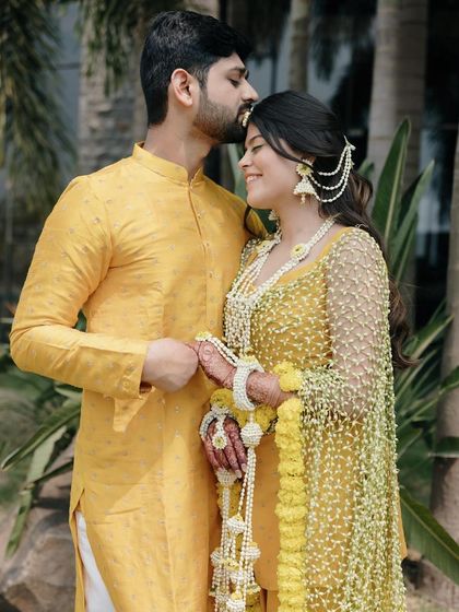 A sweet moment between the couple during the Haldi ceremony. The bride's look is fresh and effortless, with custom floral jewellery and glowing skin.