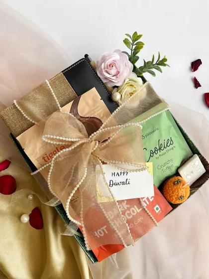 A beautifully wrapped tray hamper for Diwali, filled with a variety of cookies and chocolates. The organza and pearl bow adds a touch of elegance to the presentation.