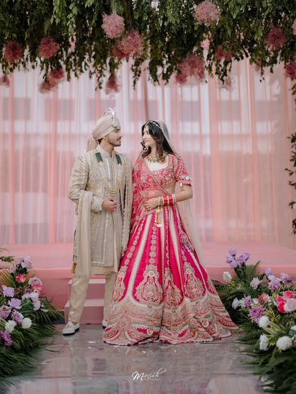 A beautiful portrait of the couple under a canopy of flowers. The stunning decor and their elegant attire come together to create a picture-perfect wedding memory.
