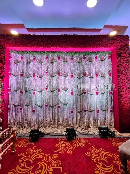 A complete view of the stage for a naming ceremony. The floral backdrop and the beautifully decorated cradle create a grand and auspicious atmosphere for welcoming the new member of the family.