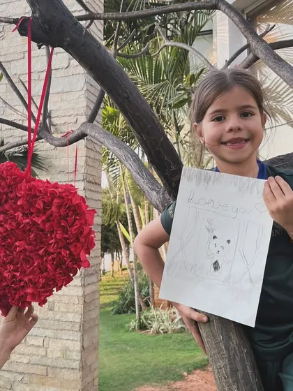 This young artist shows off her sweet panda drawing, complete with a bamboo background, while enjoying the fresh air.
