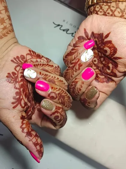 I am obsessed with creating the perfect bridal nails. This set features vibrant pink, gold glitter, and a white marble accent nail, all designed to complement the beautiful wedding mehendi.