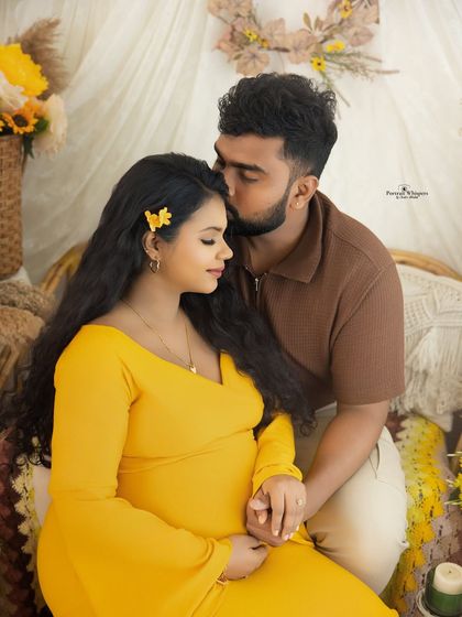 A tender moment between a couple, with a loving kiss on the forehead. The warm tones of their outfits complement the sunny yellow theme perfectly.