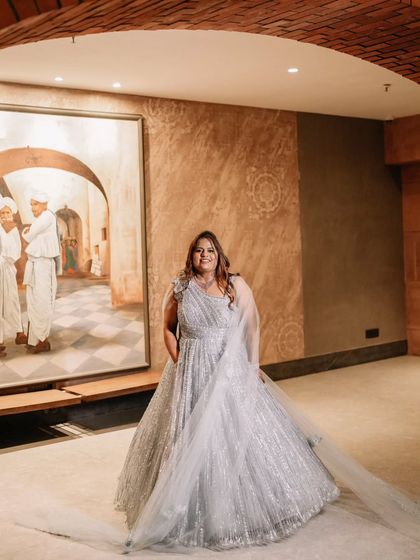 A glamorous sangeet look in a silver-grey gown. The makeup is modern and chic, with a focus on glowing skin and defined eyes.