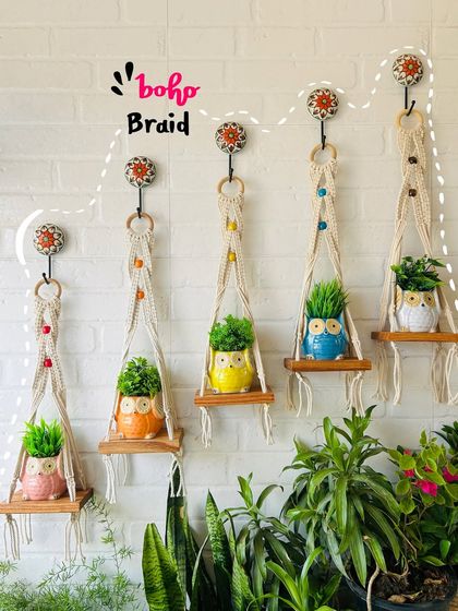 A full view of our 'Boho Braid' macrame shelves, showcasing how you can create a beautiful, staggered display. Paired with our colorful owl planters, they bring a unique, artisanal charm to your wall.