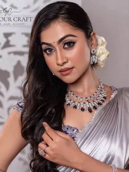 A modern and chic look featuring a silver satin saree. The lighting is clean and bright, highlighting the sheen of the fabric and the sparkle of the diamond jewelry.