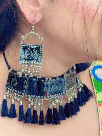 Another angle of the black tassel choker and earrings, highlighting the peacock motif on the silver plates.