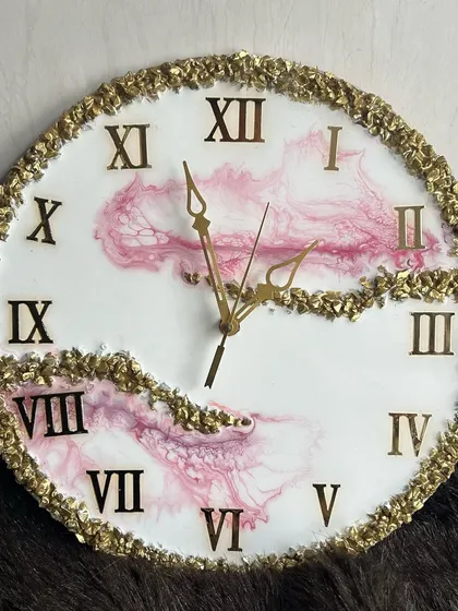 A soft pink and white resin clock with a full border of gold crystals, creating a very glamorous look.