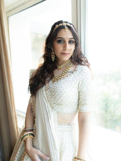 A full-length portrait of the bride in her elegant white lehenga. The natural light and her confident pose make for a stunning and modern bridal shot.