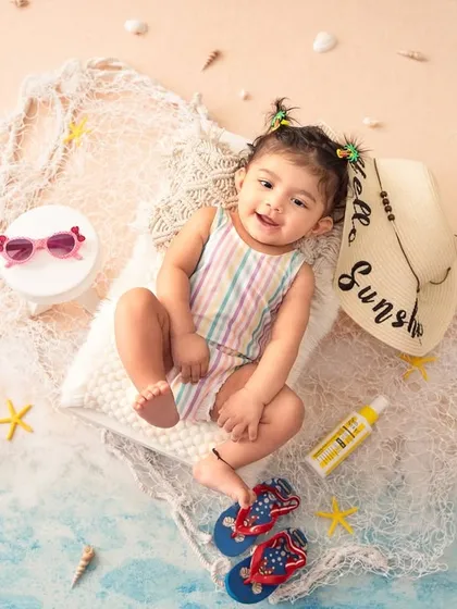 A full view of the indoor beach setup, complete with sand, shells, and a "Hello Sunshine" hat. It's a perfect backdrop for a six-month or one-year shoot.
