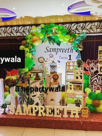 A full stage setup for a jungle safari first birthday. The large backdrop, light-up name, and photo milestone board make it a complete and memorable display.