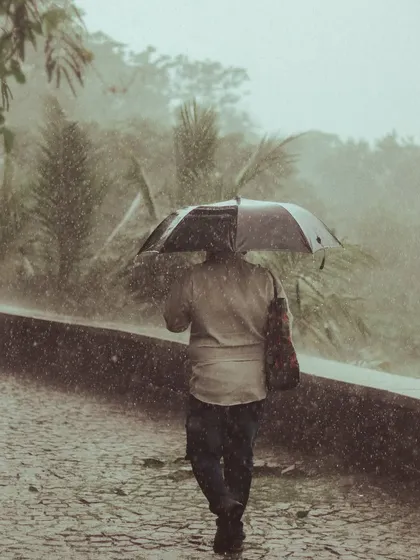 A person walks alone with an umbrella during a heavy downpour. The motion of the rain is frozen in this shot, creating a very dramatic and immersive feel.