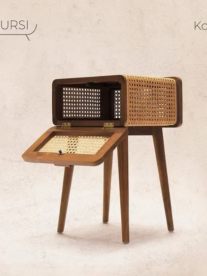 The 'Koshi' bedside table, a perfect blend of mid-century style and modern functionality. The body is crafted from teak, with a unique flip-top storage compartment featuring rattan panels.
