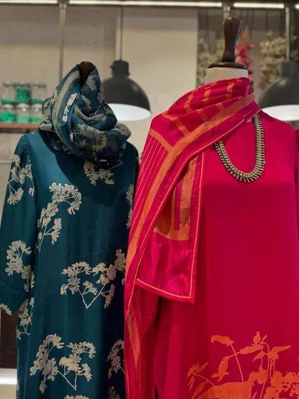 A display of Avni Bhuva's printed silks. The deep teal and bright pink kurtas feature elegant botanical prints, perfect for sophisticated festive wear.