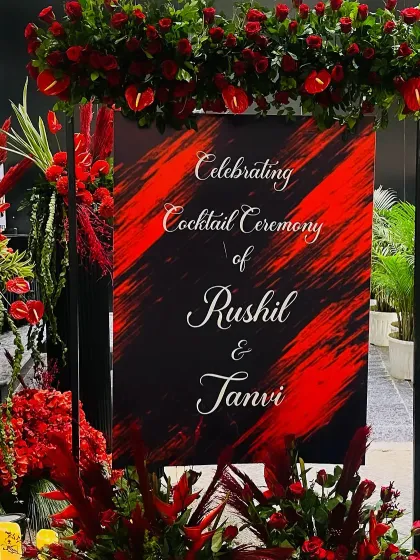 A bold and artistic welcome sign for Rushil and Tanvi's cocktail ceremony, matching the dramatic red and black theme.