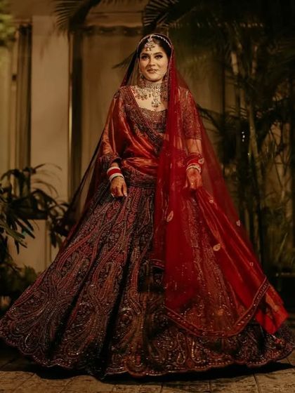 A full length portrait of the bride in her stunning deep red lehenga. The rich color and intricate embroidery are captured in beautiful detail.