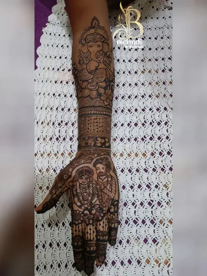 This design features a realistic couple portrait on the palm, with a beautifully detailed Ganesha figure on the forearm for blessings.