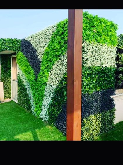 This outdoor structure is covered in a striped pattern of artificial greenery. Using dark green, light green, and white foliage creates a bold, modern look.