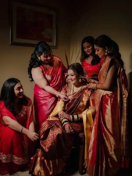 A heartwarming candid shot of the bride surrounded by her bridesmaids and family, sharing a moment of joy and support as they help her get ready.