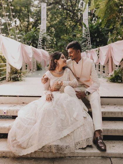 The couple seated on the steps at their engagement venue, sharing a romantic moment.