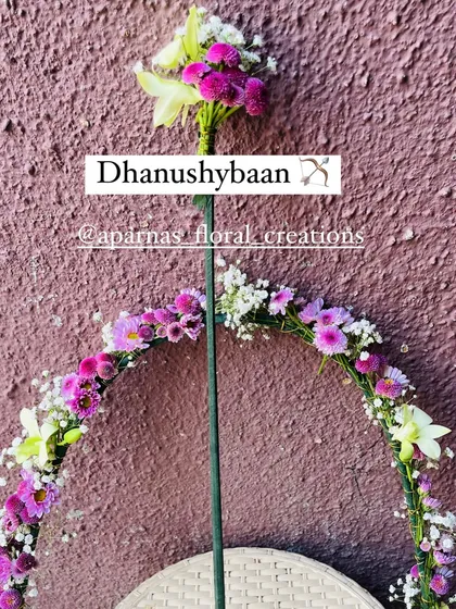 A fresh floral Dhanushbaan (bow and arrow) prop for a Dohale Jevan ceremony. This one is decorated with purple and white flowers.