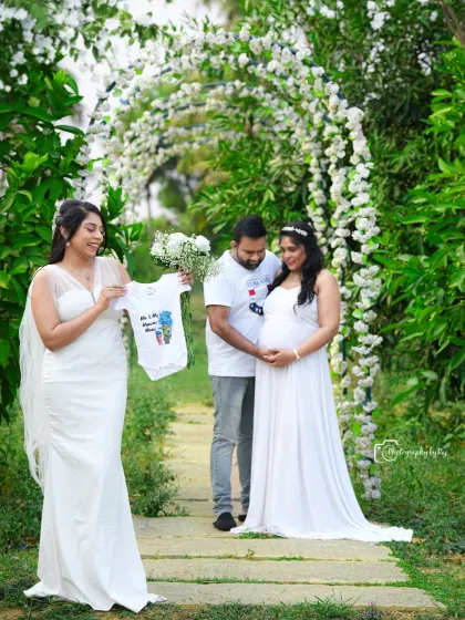 A fun outdoor shot with friends, holding up a baby onesie to celebrate the upcoming arrival.