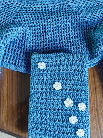 I love creating matching sets! Here is a breezy, blue crochet crop top paired with a custom book cover, both detailed with delicate white daisy flowers. It’s a perfect example of how I blend fashion with functional art.