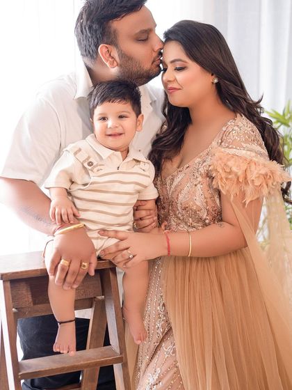 A tender family moment with dad giving his son a kiss on the forehead. The warm, earthy tones of their outfits complement the boho studio setting.