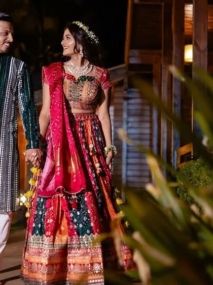 A vibrant night-time shot of a couple walking hand-in-hand, their colorful, sequined outfits shining under the lights.
