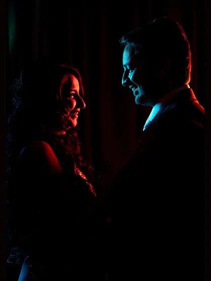 A silhouette portrait of the couple, using dramatic red and blue backlighting to create an intimate and moody reception shot.