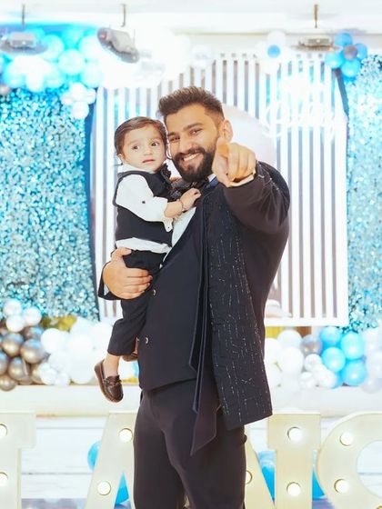 Father and son moments are truly special. This is a candid portrait of the birthday boy with his dad, sharing a happy moment in front of the vibrant party decorations.