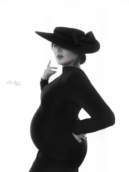 A powerful and confident pose in black and white. The angle and the dramatic hat create a high-fashion look, proving that maternity portraits can be both artistic and empowering.