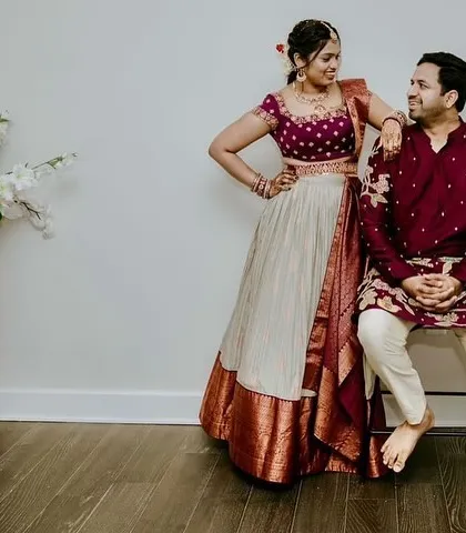 A playful moment between a couple, the bride in a classic ivory and maroon lehenga and the groom in a coordinating maroon kurta.