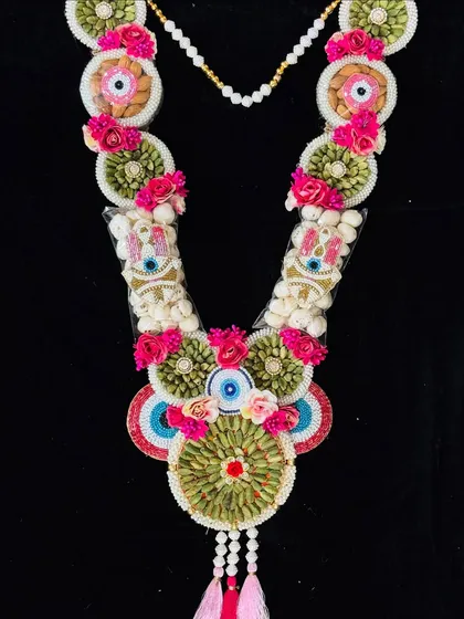 This evil eye themed garland is made with saunf (fennel seeds) and other treats, adorned with pink flowers.