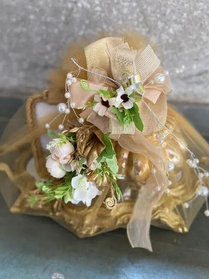 A close-up of our classic gold-wrapped gift, showcasing the intricate bow made of tulle, pearls, and soft florals. This image emphasizes the delicate, handcrafted details that define our brand.