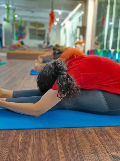 A student relaxes into Paschimottanasana (Seated Forward Bend), a fundamental posture for calming the mind and stretching the entire back body.