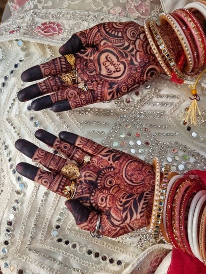 This bride chose to have her partner's name written inside a heart on one palm, a sweet and personal touch to her intricate bridal mehndi.