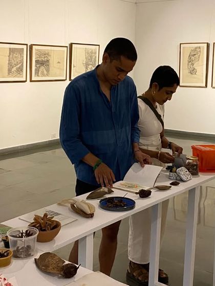 Visitors looking through the artist's books and examining the collection of natural and found objects in 'Bring me Flowers'.
